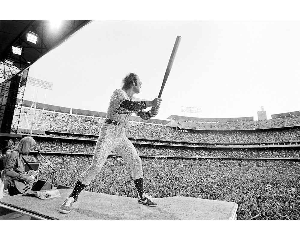 Elton John peforming with a baseball bat, 1975