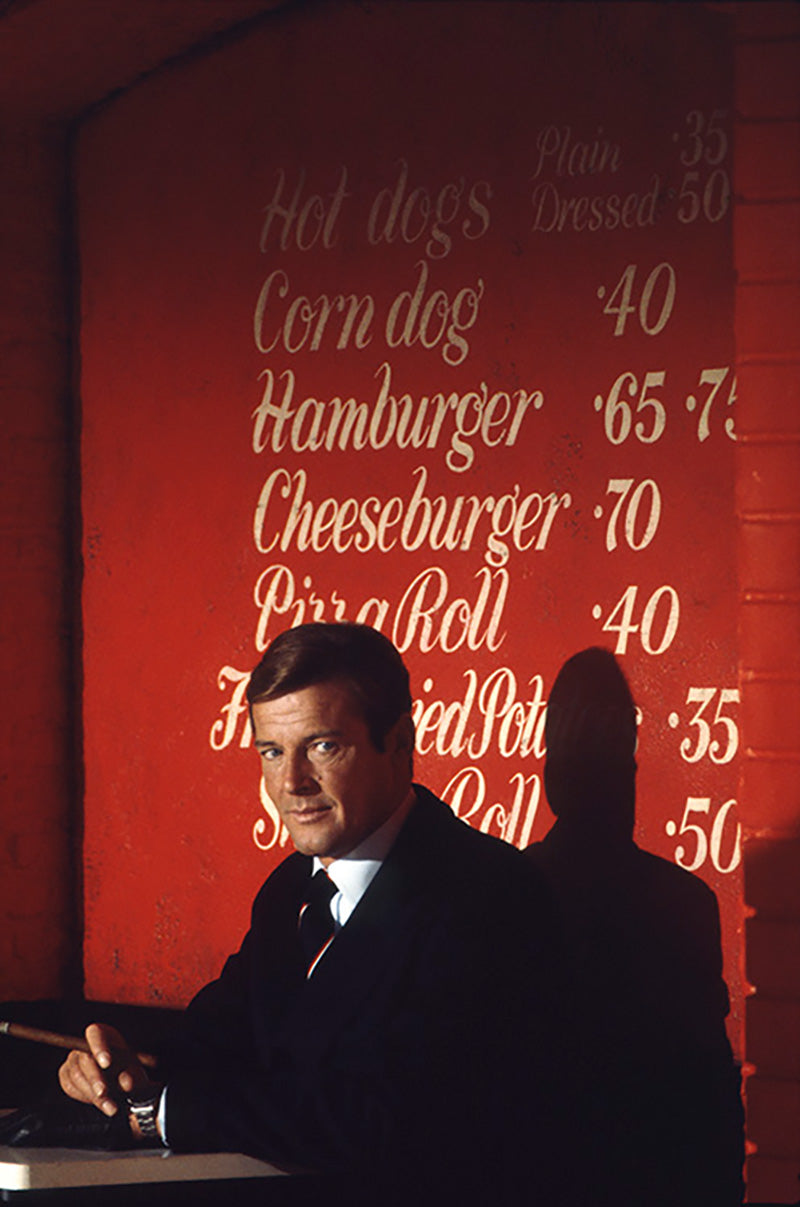 Roger Moore as James Bond smoking a cigar in a diner on the film set of 'Live and let die', 1973